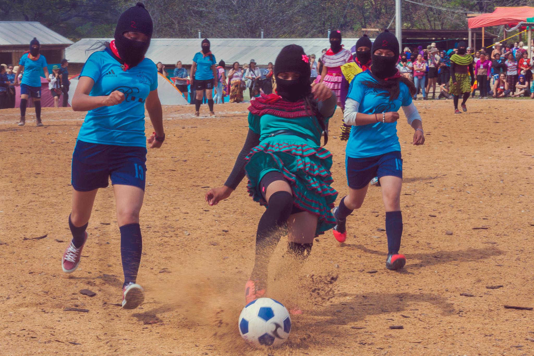 Mujeres zapatistas con pasamontañas juegan fútbol en el Primer encuentro de Mujeres que Luchan (2018), Chiapas, Caracol Morelos. 